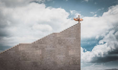 child dressed as an aviator with cardboard plane on a cliff dreams of an adventure.の写真素材