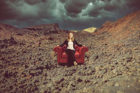 woman sitting on an armchair in a desolate placeの写真素材
