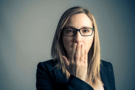 portrait of woman covering her mouth on gray backgroundの写真素材
