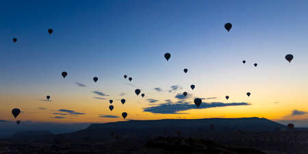 hot air balloons take off at sunrise over the city of goreme in turkeyの写真素材