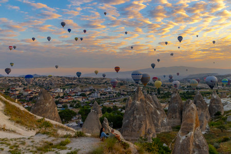 GOREME / TURKEY - June 30, 2022: tourists watch the spectacle of the hot air balloons flying above them at dawn.のeditorial素材