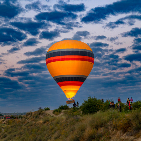 GOREME / TURKEY - June 30, 2022: hot air balloon flies over the tourists near the hills of goreme.のeditorial素材