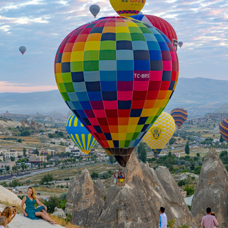 GOREME / TURKEY - June 30, 2022: tourists take pictures with hot air balloons in the background