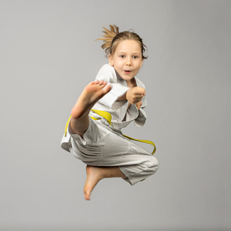 girl performs martial arts flying kick, studio shotの写真素材