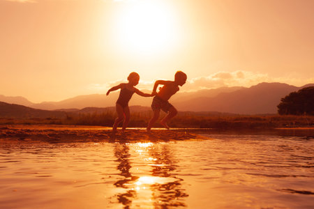 children run happily on the beach at sunsetの写真素材