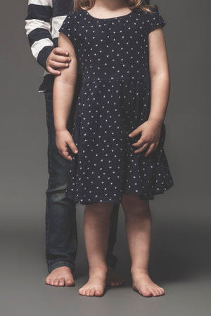 portrait of sibling children barefoot, face not in view.