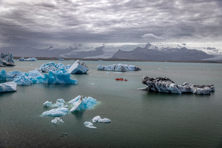 Kayakers glacial jokulsarlon lagoon icebergs mountains background Icelandの写真素材