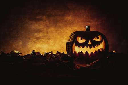 Spooky halloween pumpkin is glowing autumn leaves backgroundの写真素材