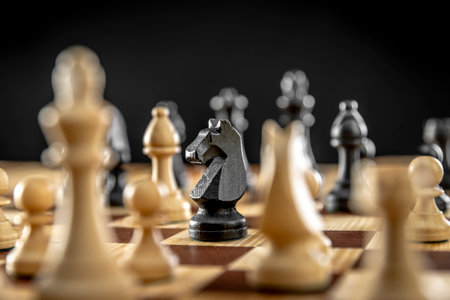 Black knight chess piece standing on wood chessboardの写真素材