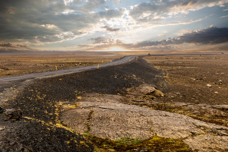 Asphalt road volcanic landscape in iceland under cloudy sky during sunsetの写真素材