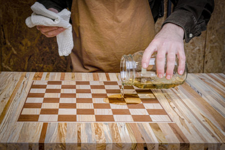 Carpenter varnishing chessboard table made of different woodの写真素材