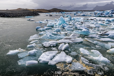 Icebergs floating in the jokulsarlon glacier lagoon in iceland under cloudy skyの写真素材