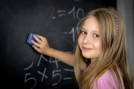 Young girl erasing math equations on a blackboardの写真素材
