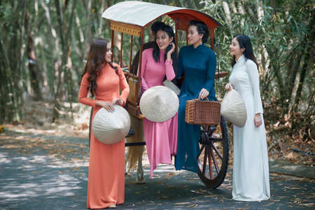Ho Chi Minh city, Viet Nam: Vietnamese girls wear white ao dai and ride on a horse-drawn carriage on a country road in Vietnamの写真素材