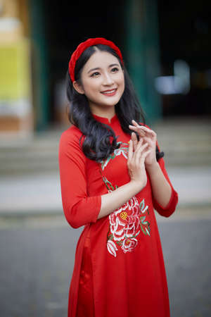 Ho Chi Minh City, Vietnam: Portrait of a brilliant Vietnamese girl in a red ao dai to welcome the Vietnamese traditional New Yearの写真素材
