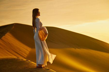 Ninh Thuan Province, Vietnam: portrait of a beautiful Vietnamese girl wearing a white ao dai on the sand dunes at dawnの写真素材