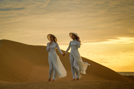 Ninh Thuan Province, Vietnam: portrait of a beautiful Vietnamese girl wearing a white ao dai on the sand dunes at dawnの写真素材