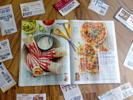 An overhead shot of clipped coupons, scissors and a magaine.のeditorial素材