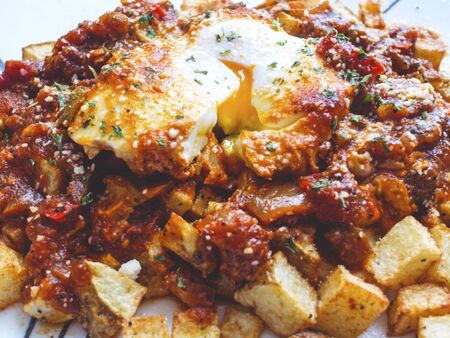 Eggs poached in tomato sauce over fried potatoes.