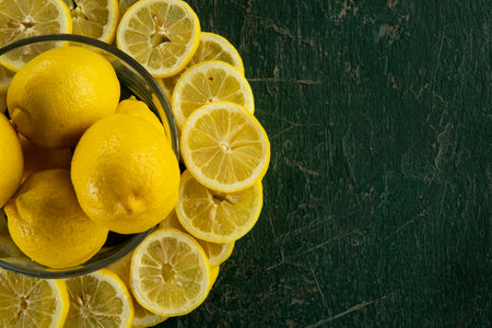 whole and sliced lemons arranged in a circular pattern on a green painted rustic peeling old tableの写真素材