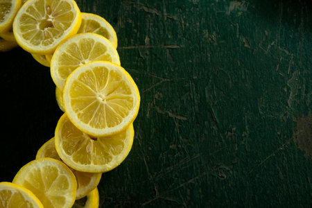 whole and sliced lemons arranged in a circular pattern on a green painted rustic peeling old tableの写真素材