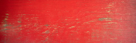 close up of old red painted board with flaking weathered paint and exposed wood grainの写真素材