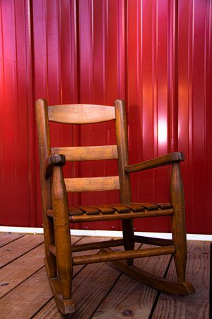 wooden child's rocking chair on porch with metal sidingの写真素材