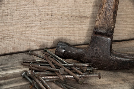 close up of hammer with nails on wood with black background with reduced vibrance, grungy, old, antique, vintageの写真素材
