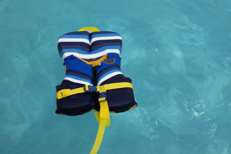 blue and yellow life preserver life vest floating in blue water with no people,  copy space, used to...