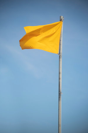 windy day weather, beach day, yellow warning flag, swim conditions, ocean safety caution flag for conditions of the water and wavesの写真素材