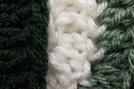 close-up of vertical rows of crochet stitches in a sage green, hunter green and white blanket,...