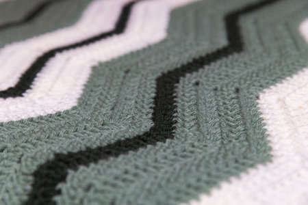 close-up of grandma's retro zigzag striped blanket, in white, dark green and sage green, crocheted...
