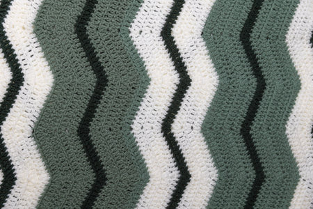 close-up of grandma's retro zigzag striped blanket, in white, dark green and sage green, crocheted...