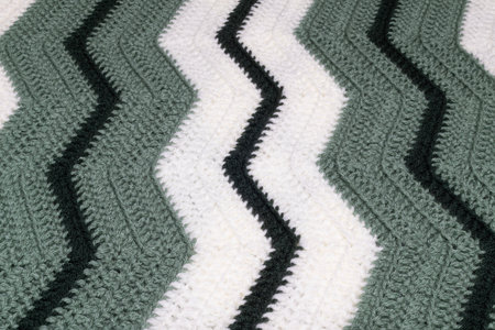 close-up of grandma's retro zigzag striped blanket, in white, dark green and sage green, crocheted...