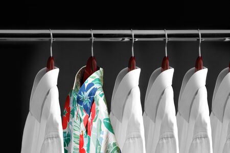 Tropical shirt between white shirts hanging inside a closetの写真素材