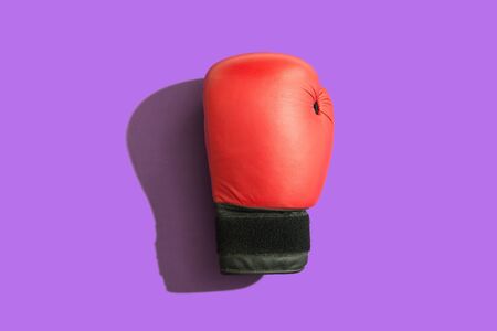 Boxing glove with shadow over a purple background