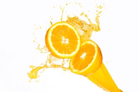 Orange juice splashing on half oranges against a white backgroundの写真素材