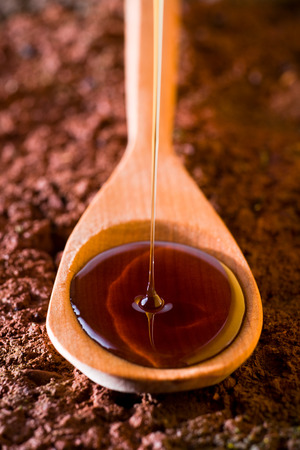 Liquid honey poured on a wood spoonの写真素材