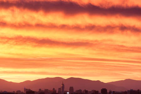 Skyline of downtown Santiago de Chile with a large cloudy sky at sunsetの写真素材