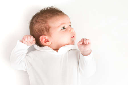 A view from above of a newborn boy on a white background with his hand closed