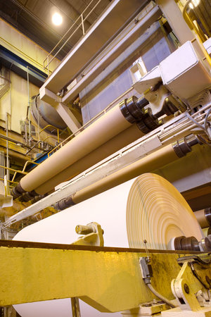 Big rolls of paper coming out of the machinery in a paper mill plant.の写真素材