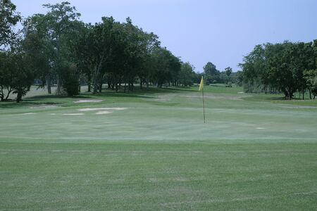 A yellow flag hole in a golf fieldの写真素材