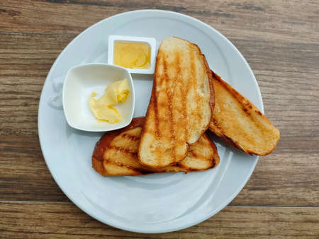 Toasts with butter and jam in white plate on wood tableの写真素材