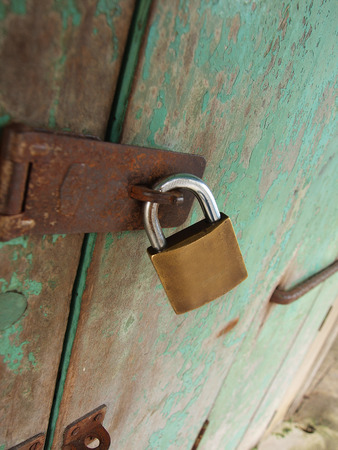 Old green door locked with a rusty padlock.の写真素材