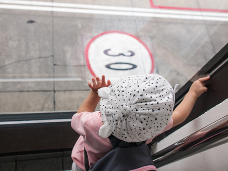 The child touching the glass wall and looking at the number  on the street.の写真素材