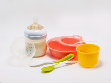 Containers such as baby bottles, rice dishes, cutlery and glasses in white background.の写真素材