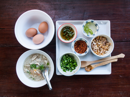 Boiled rice condiments such as chili powder, garlic, coriander and poached eggs on the wooden table background.の写真素材