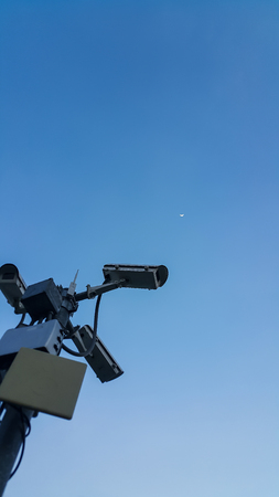 Many CCTV cameras are on the pillars and there is evening sky behind.
