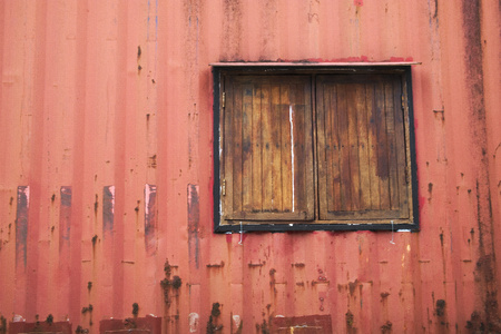 The old walls are made of metal sheet, painted red. And wooden windows.の写真素材