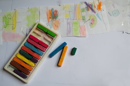 Drawing on the imagination of children with chalk colors in various colors on white background paper.の写真素材